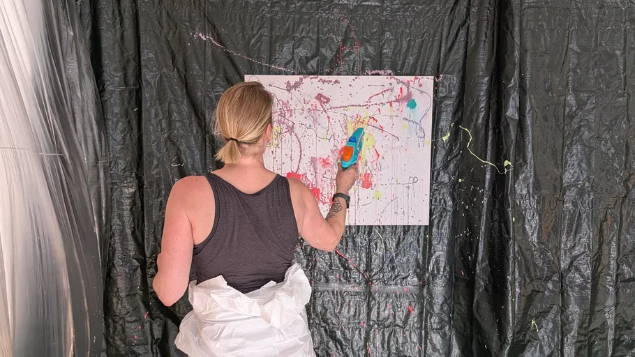 Person painting abstract art with a toy gun.