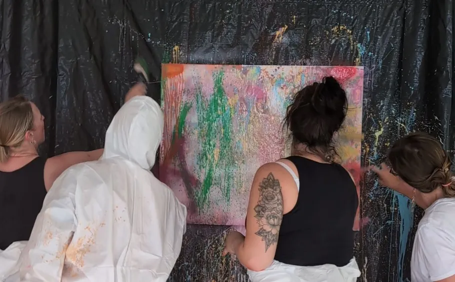 People painting large abstract canvas indoors.