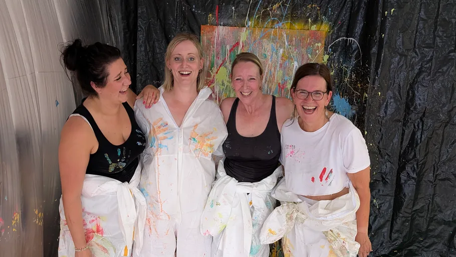 Four women smiling with paint-splattered clothes.