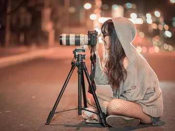 Eine Person fotografiert mit einer Kamera auf einem Stativ nachts.