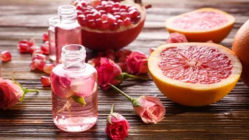 Flaschen mit Rosenöl, Grapefruit und Blumen.