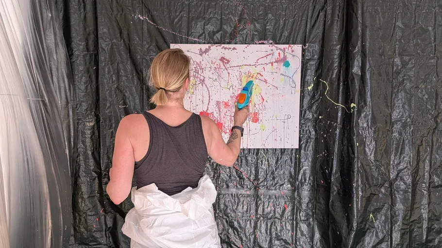 Person sprüht Farbe auf Leinwand im Studio.