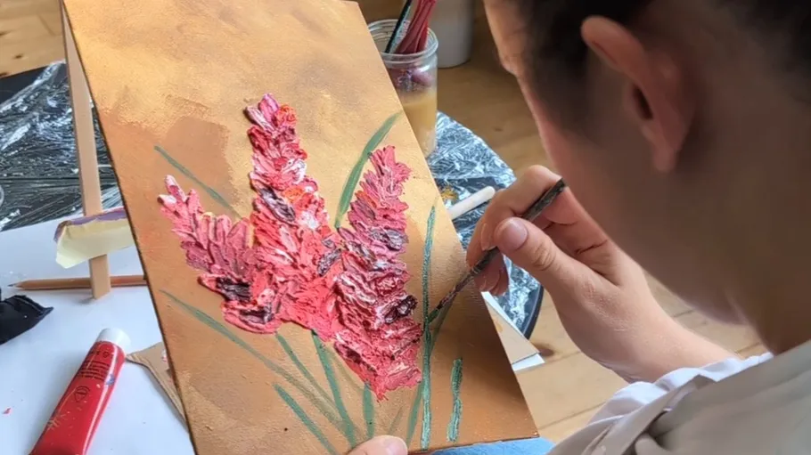 Person painting red flowers on canvas.