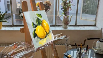 Painting of lemons on easel in art studio.