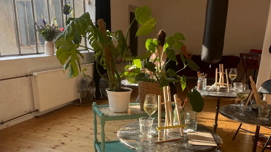 Indoor cafe with plants and painting easels.