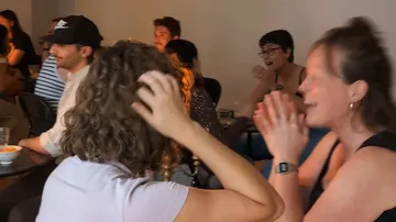 Gruppe von Menschen klatscht und lacht drinnen.