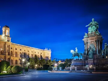 Equestrian statue stands in front of a historic building at night.