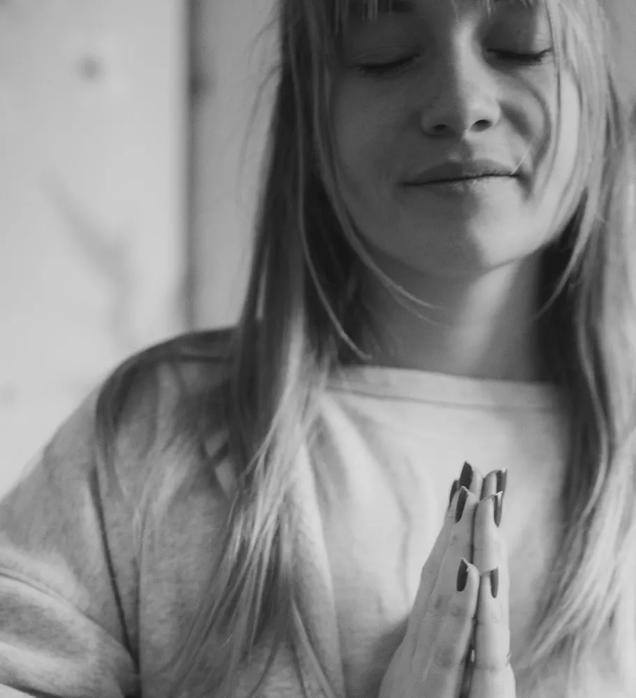 Woman meditating with closed eyes indoors.