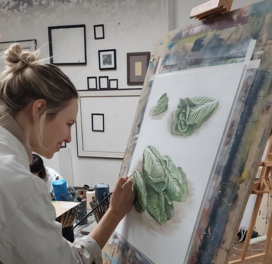 Frau malt Salatblätter im Kunststudio.