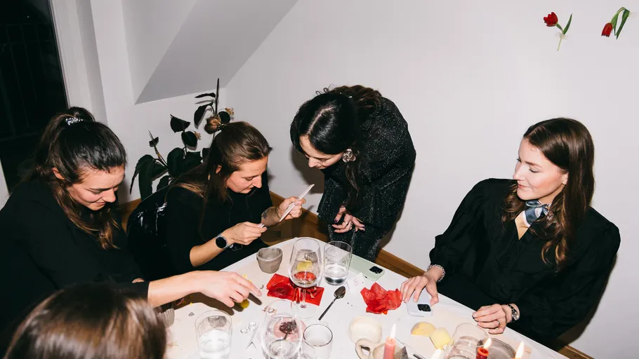 Women crafting around a table, indoor setting.