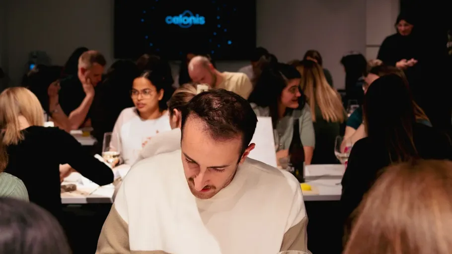 Personen sitzen in einem Besprechungsraum, fokussiert auf Papiere.