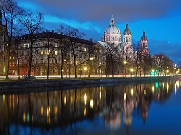 City view with illuminated buildings and reflecting water.