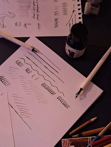 Calligraphy pens and paper with practice strokes.