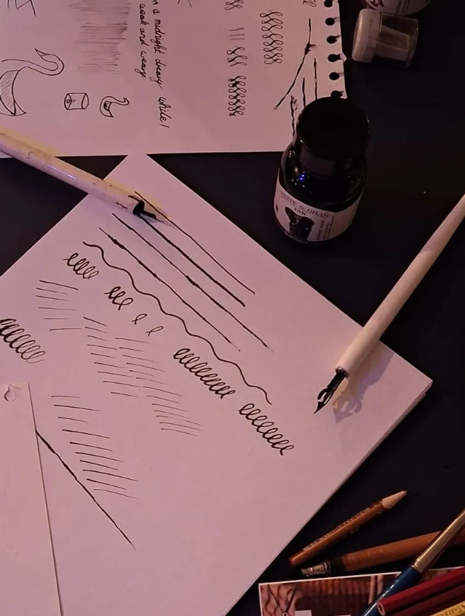 Calligraphy pens and paper with practice strokes.