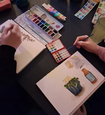 People painting with watercolors on a table.