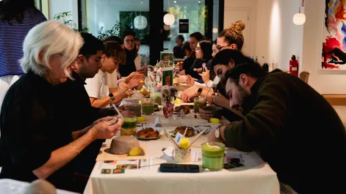 Leute essen zusammen an einem langen Tisch drinnen.
