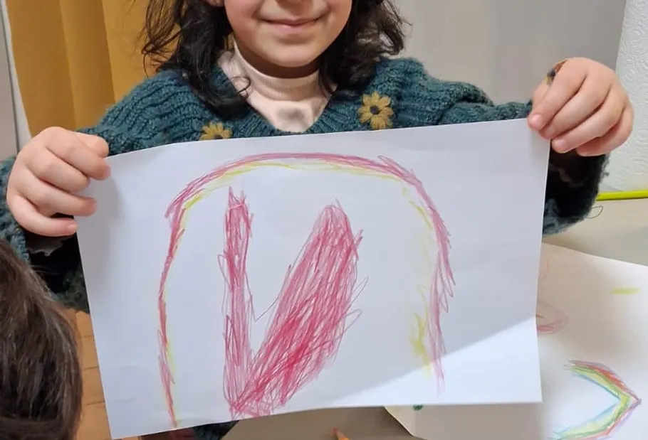 Kind hält Zeichnung im Klassenzimmer.