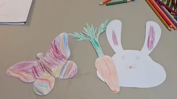 Colored paper butterfly and rabbit on table.