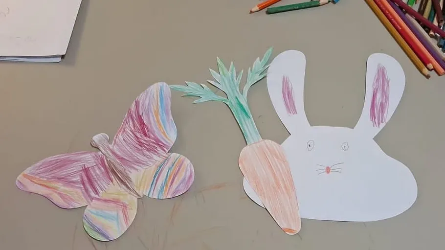 Buntes Papier-Schmetterling und Hase auf Tisch.