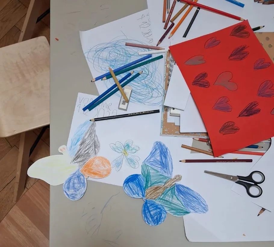 Craft table with papers, drawings, and colored pencils.
