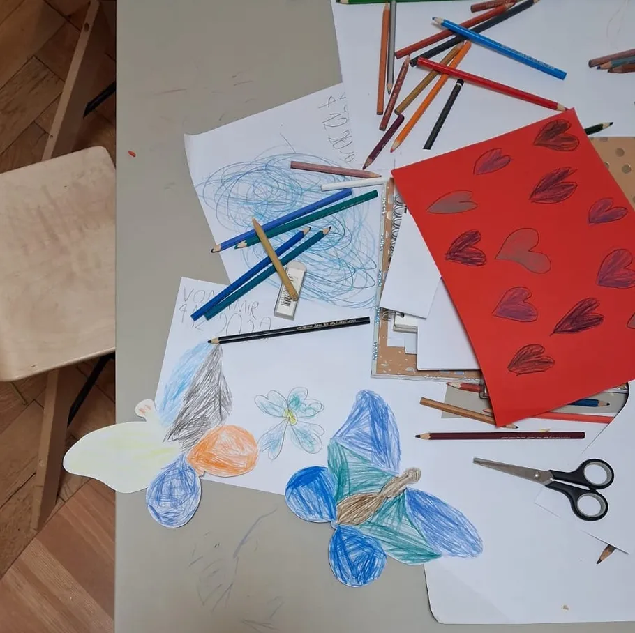 Bunte Zeichnungen und Stifte auf einem Tisch.