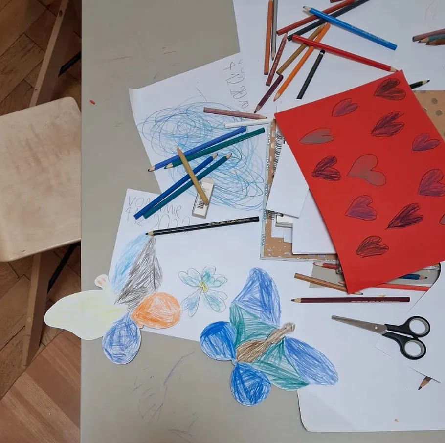 Bunte Zeichnungen und Stifte auf Tisch.