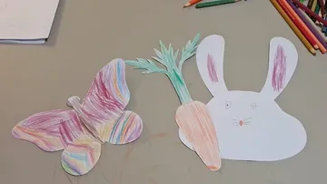 Colored butterfly and rabbit with carrot on table.