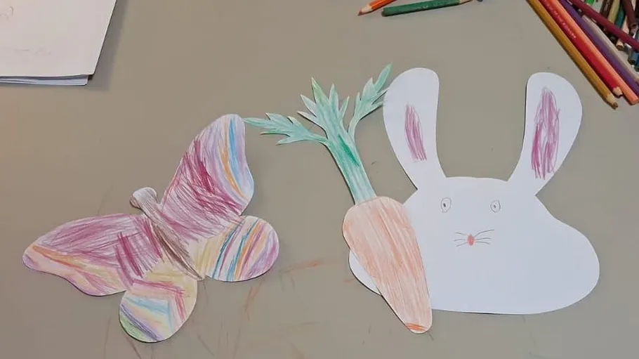 Colored butterfly and rabbit with carrot on table.