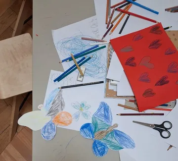 Basteltisch mit buntem Papier und Stiften.