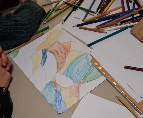 Person malt abstrakte Formen mit Buntstiften.