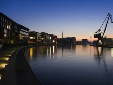 Sonnenuntergang über einem ruhigen Wasserweg mit Gebäuden.