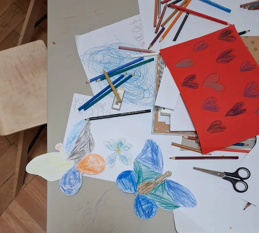 Tisch mit Kunstmaterialien und Zeichnungen.