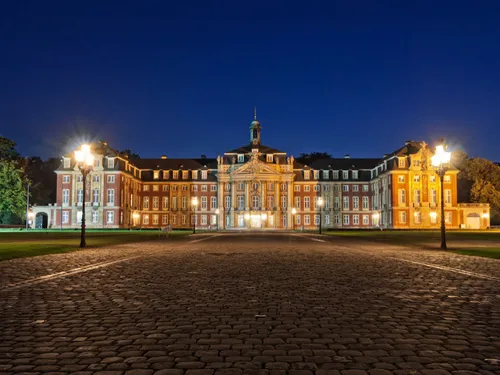 Historisches Schloss mit beleuchtetem Eingang bei Nacht.