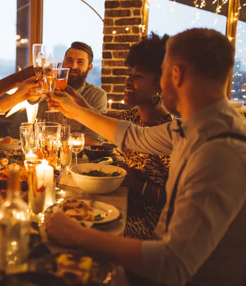 Friends toasting at a festive dinner table.