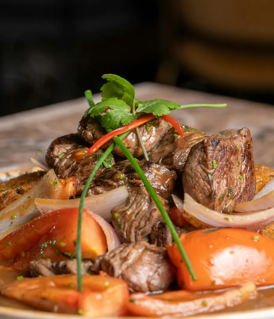 Grilled beef with tomatoes and herbs on plate.