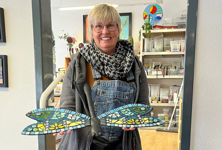 Person holding a mosaic dragonfly indoors.