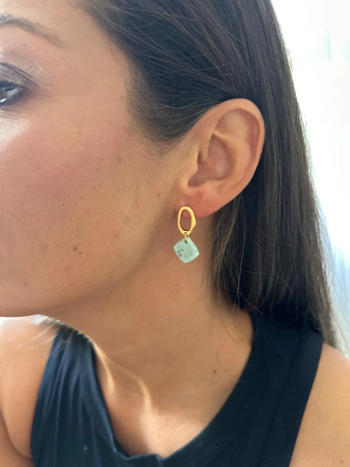 Woman wears gold and stone earring.