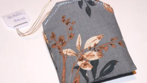 Grauer Blumen-Teebeutel mit Etikett.