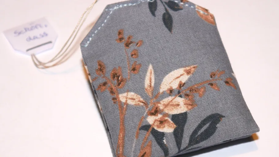 Gray floral tea bag with string tag.