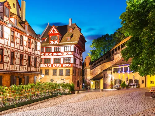 Historische Gebäude stehen an einer gepflasterten Straße bei Nacht.