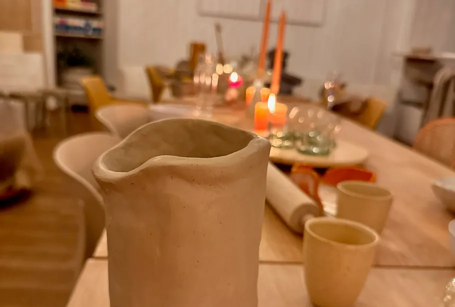 Handgefertigte Tasse auf einem schwach beleuchteten Tisch.