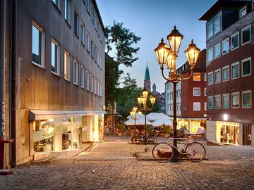 Straße mit Laternen und Fahrrad, in einem Stadtviertel.
