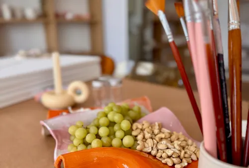 Brushes in a cup, grapes, nuts on table.