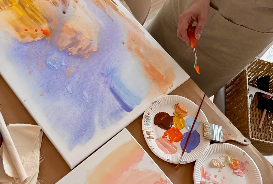 Person painting abstract art on canvas.