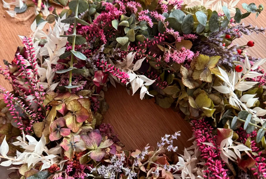 Colorful dried flower wreath on wooden surface.
