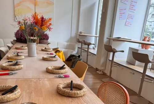 Table with flower arrangement supplies in bright room.