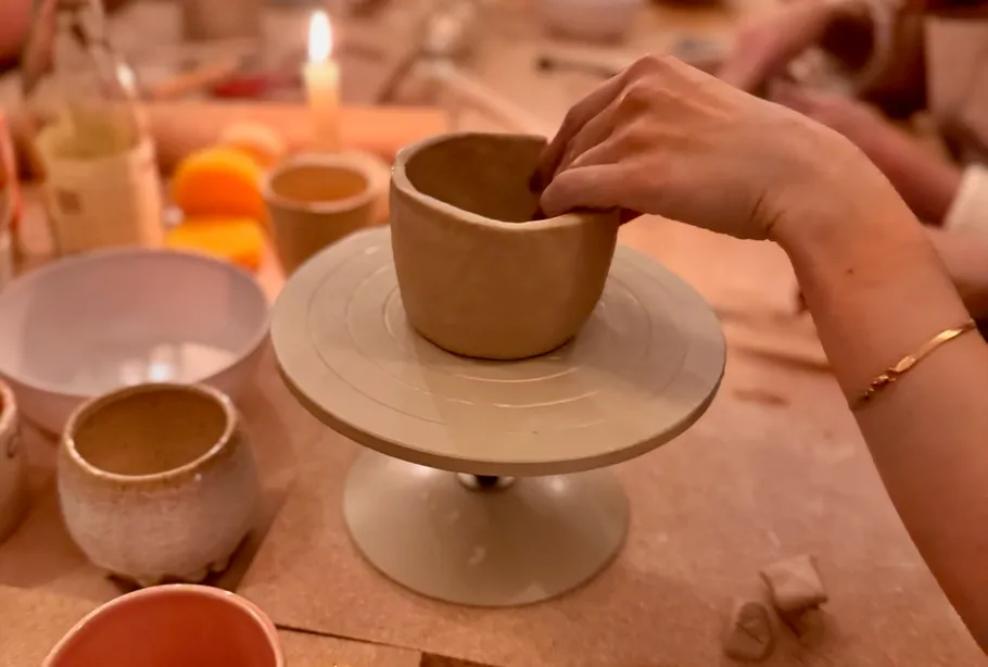 Hand shaping pottery cup on a turntable.