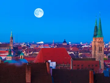 Stadtansicht mit Kirchen, Vollmond am Himmel, blaues Licht.
