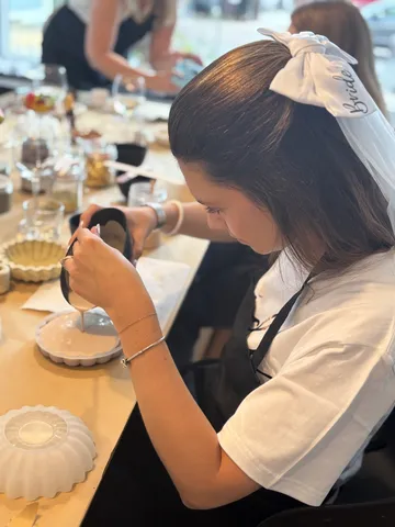 Woman decorating cake at workshop table.