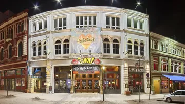 Illuminated theater exterior at night, city street.